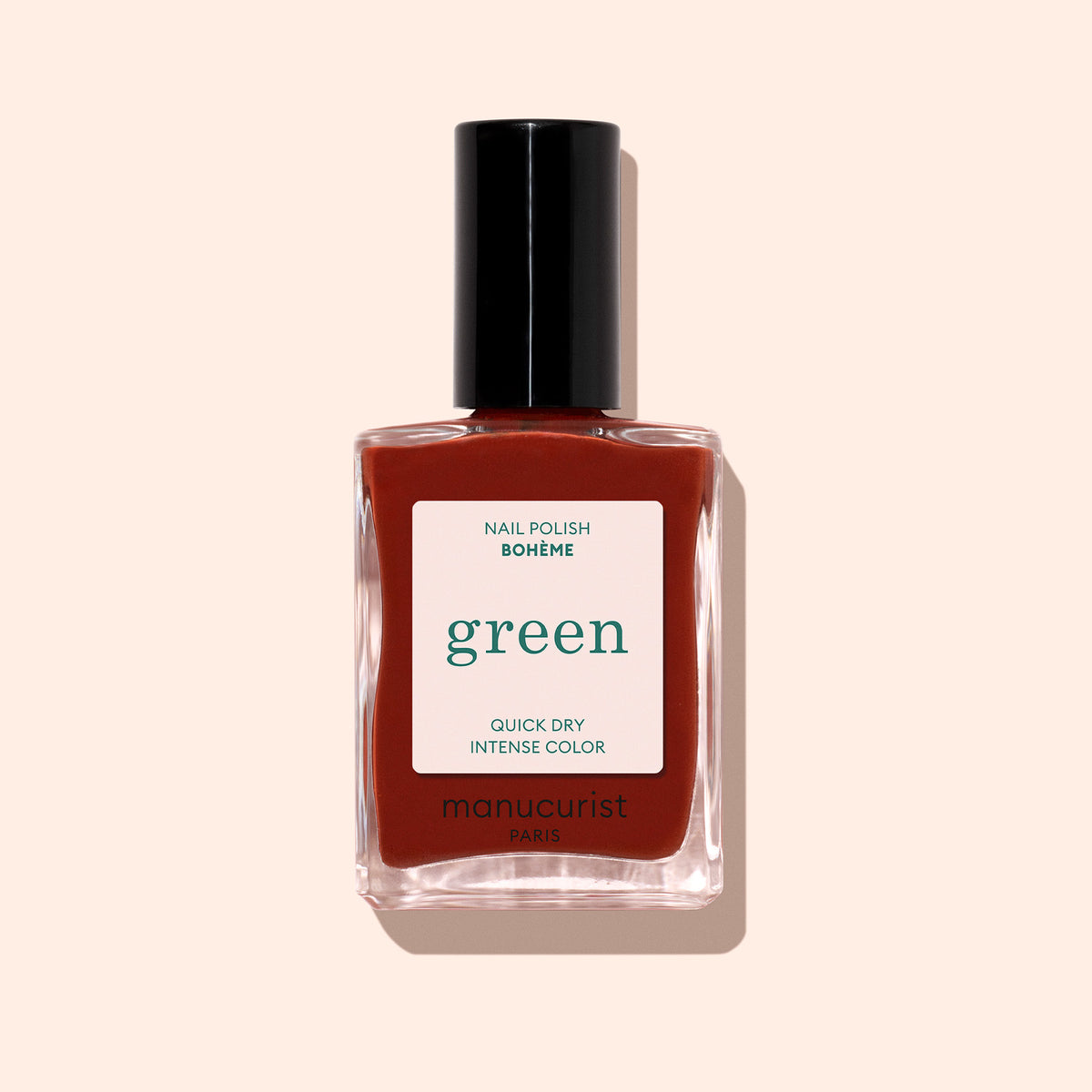 Un flacon de vernis Manucurist Bohème, portant les mentions "green" et "COULEUR INTENSE SÉCHAGE RAPIDE," présente un rouge profond aux sous-tons bruns et un bouchon noir, sur fond beige clair.
