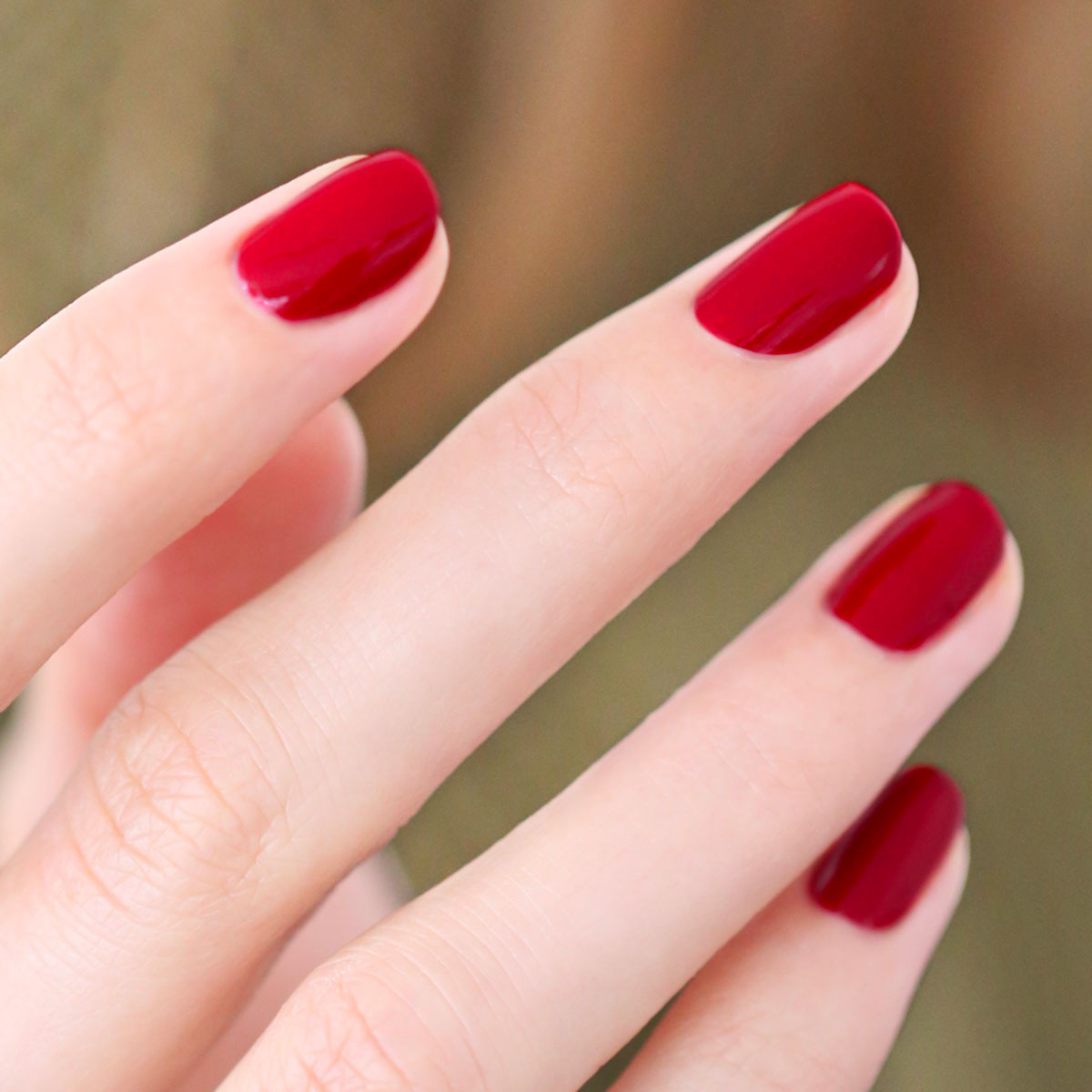 Gros plan sur des ongles parfaitement manucurés et vernis dans des teintes brillantes du trio Red, White & Blue de Manucurist, avec un fard à paupières assorti audacieux pour un look saisissant sur fond flouté.