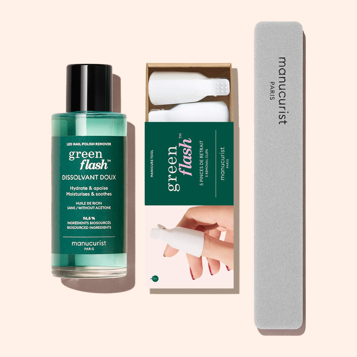 The Manucurist-us Green Flash™ Remover Clips Duo, featuring plant-based remover, two white removal clips, and a gray nail file, is displayed on a light pink background.