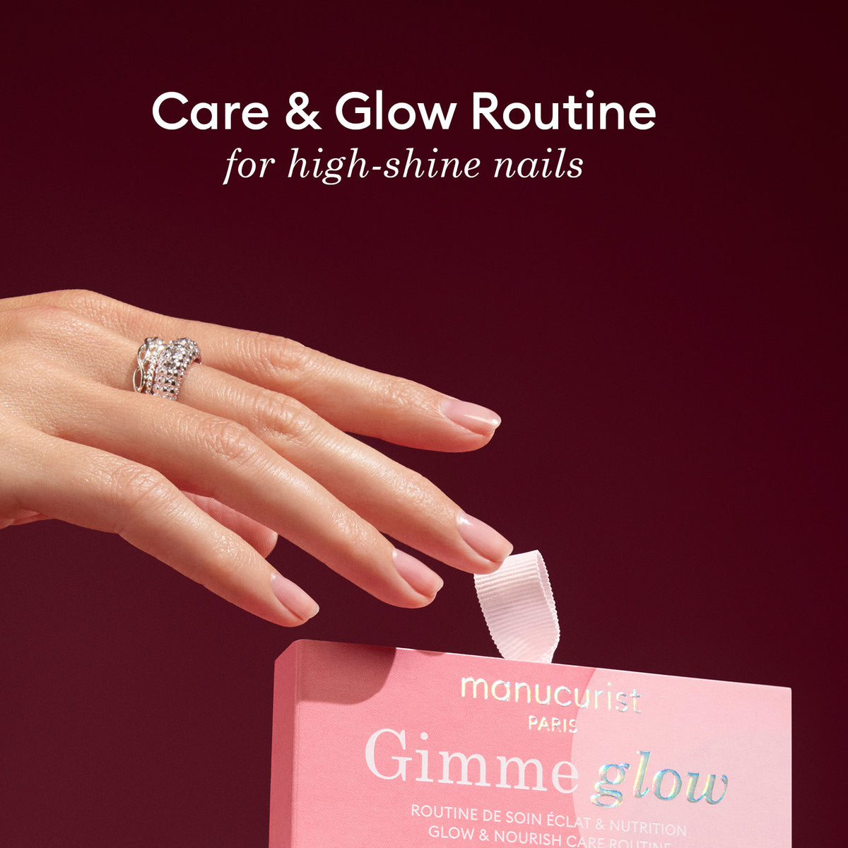A hand with glossy, manicured nails and a jeweled ring holds a pink Manucurist 5min&