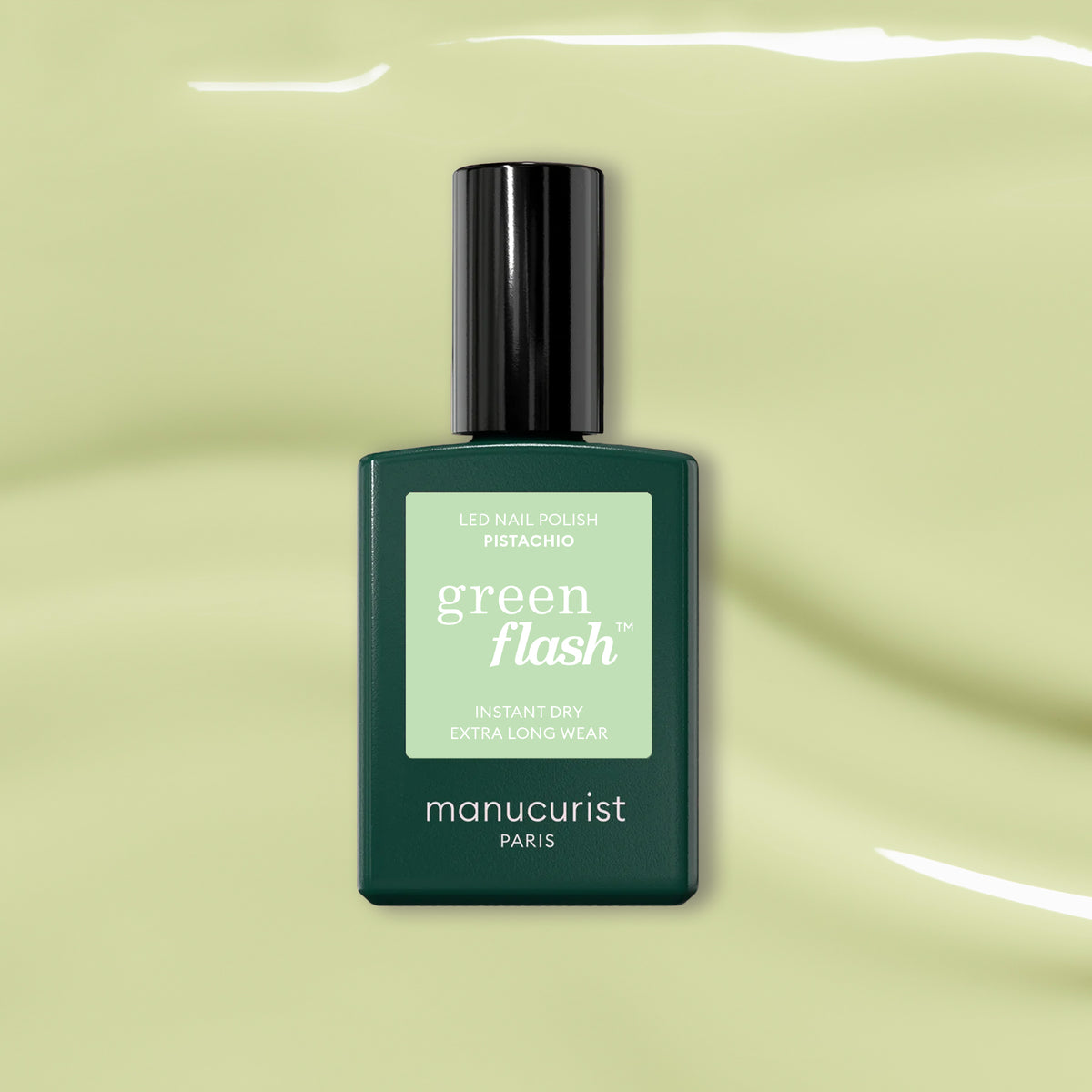 Un flacon de Manucurist Pistachio, un vernis gel LED vert pâle aux sous-tons jaunes, est présenté sur un fond vert clair brillant.