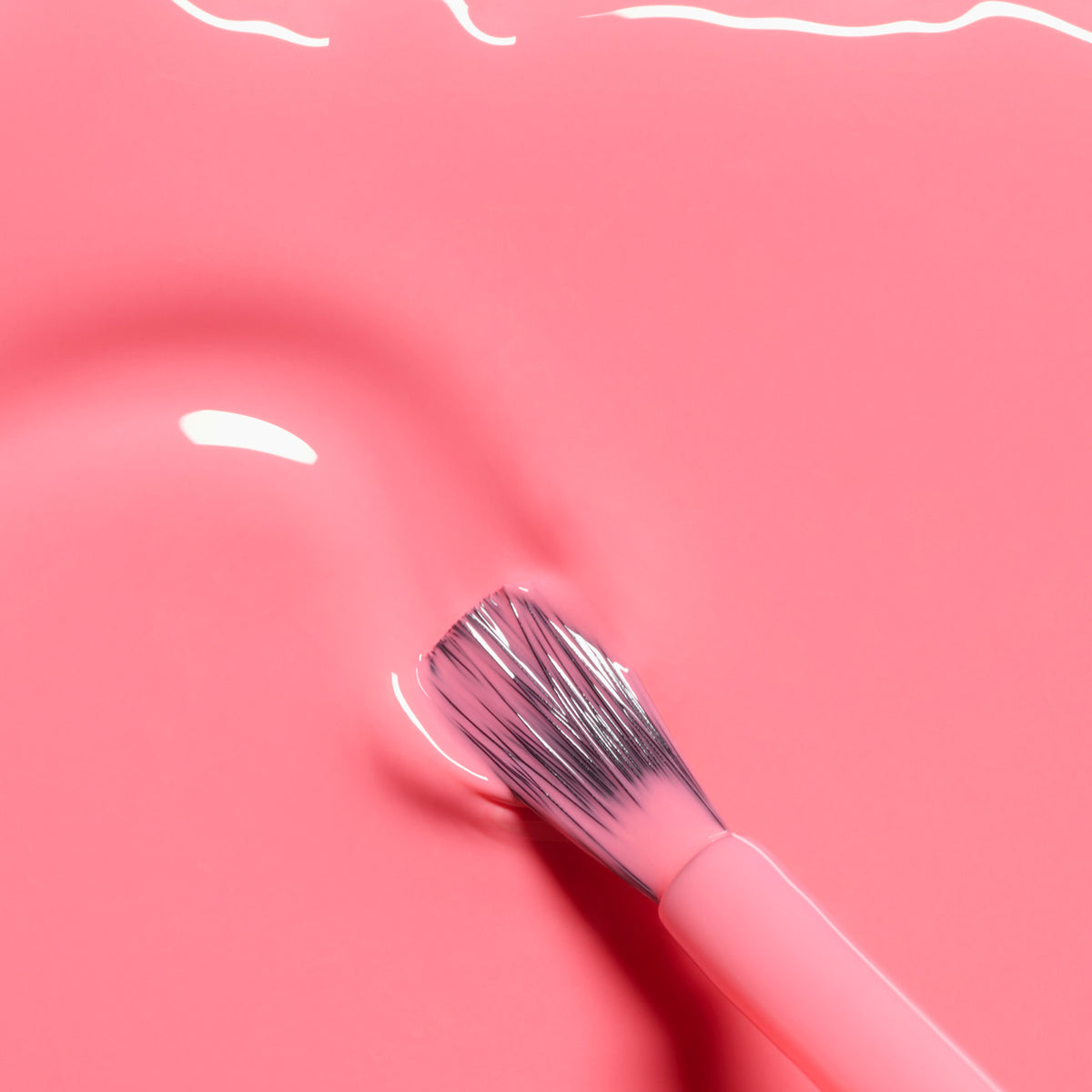 A close-up of a brush with pink bristles resting on the smooth, glossy surface of Manucurist&