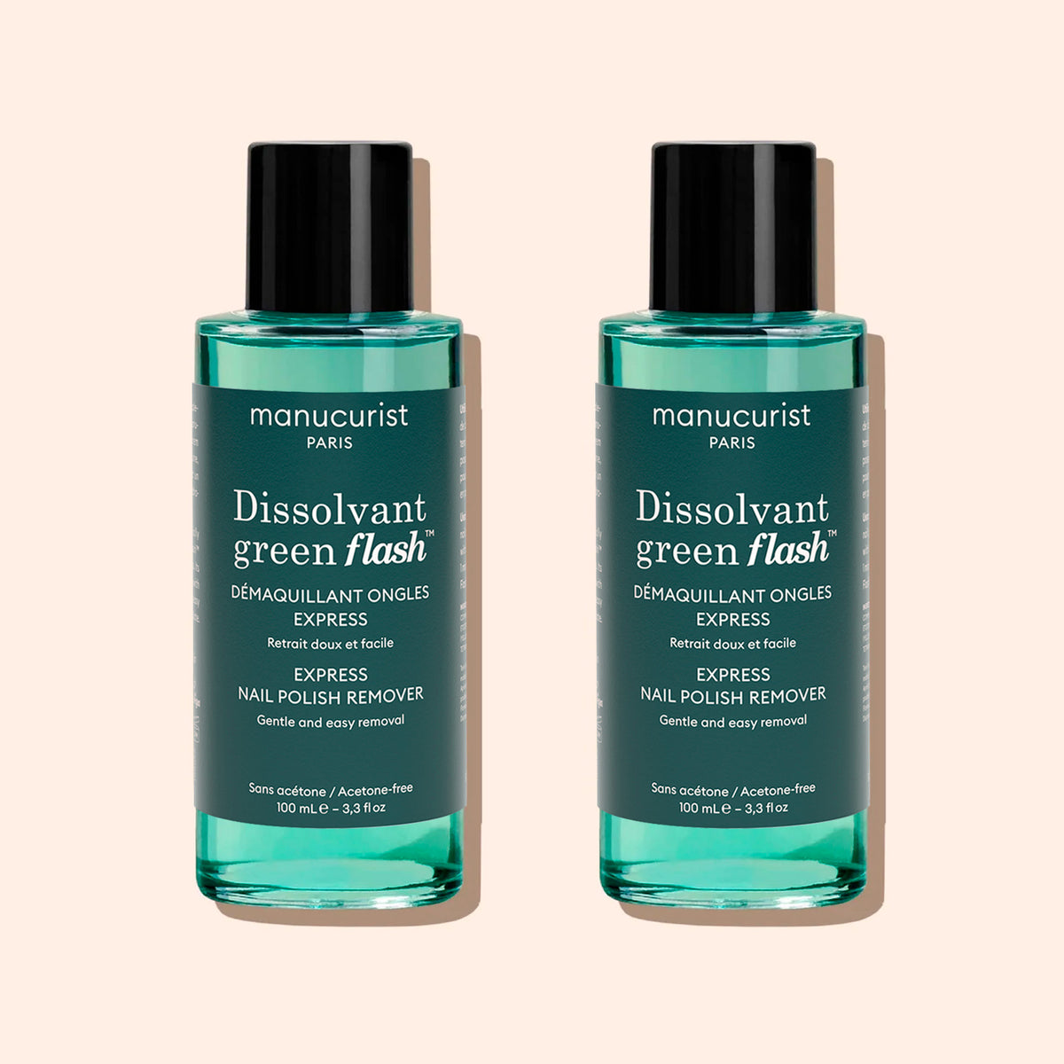 Two identical bottles of Manucurist Green Flash™ Gel Polish Remover with teal liquid, black caps, and white labels stand side by side on a beige background.