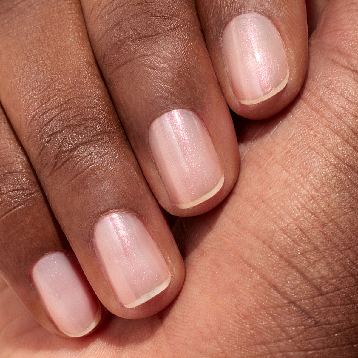 A close-up of a hand with medium brown skin, showcasing neatly manicured nails painted in Manucurist&