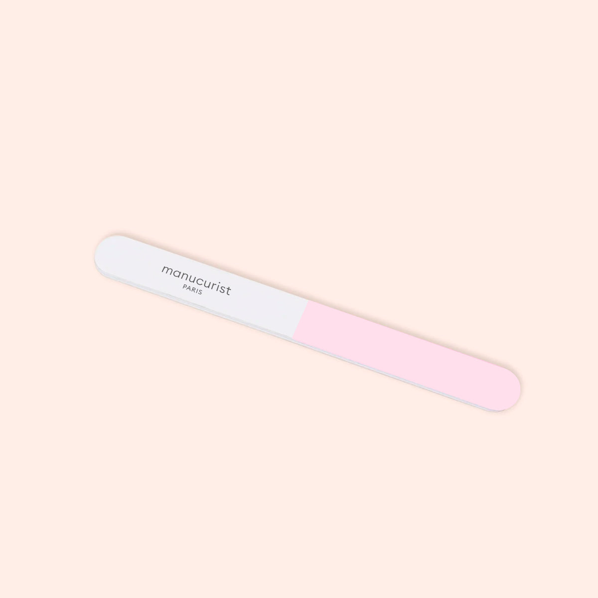 The Manucurist 3-Face Nail Buffer, featuring pink and white sections with "Manucurist" printed on the white side, is shown against a light beige background.