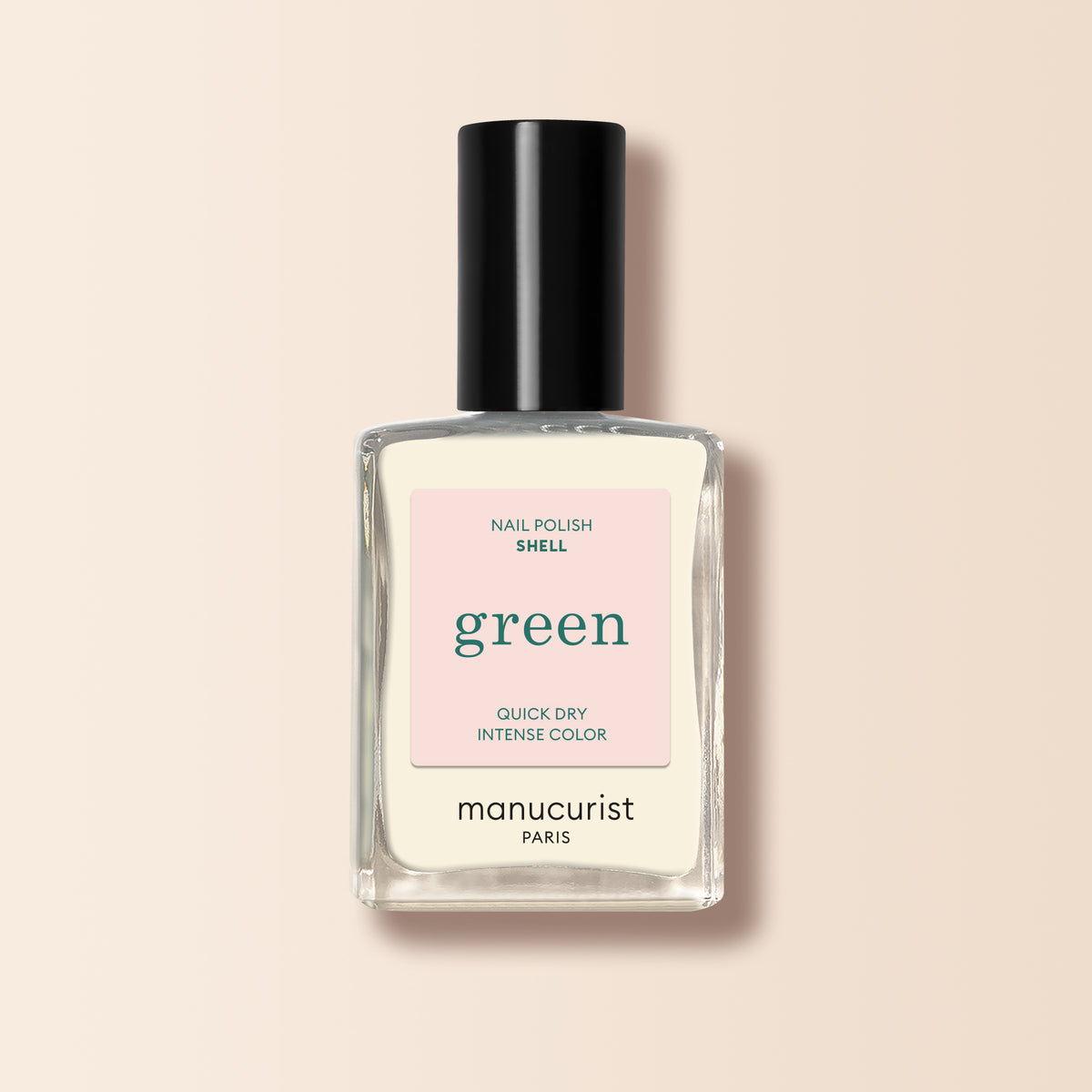 A clear glass bottle of Shell nail polish from Manucurist, with a black cap and light pink label, is displayed against a light beige background.