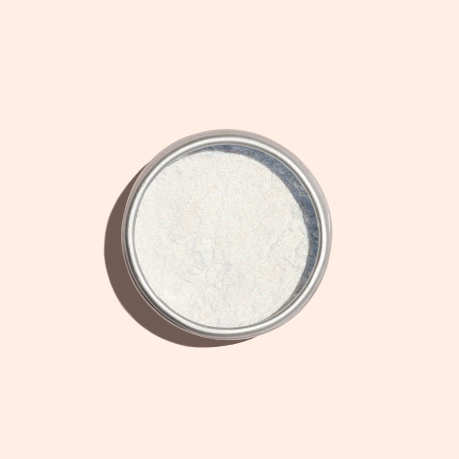 A round metal tin of Manucurist Blue Glazed Powder, a fine white manicure powder, viewed from above on a light beige background.