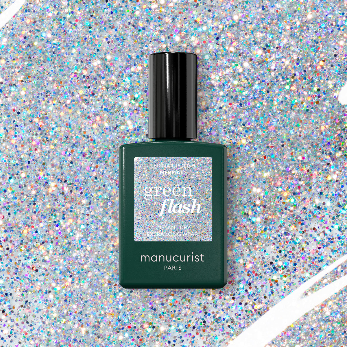 A bottle of Manucurist Mermaid Green Flash gel polish rests on a sparkling holographic glitter background that matches its glittery label.