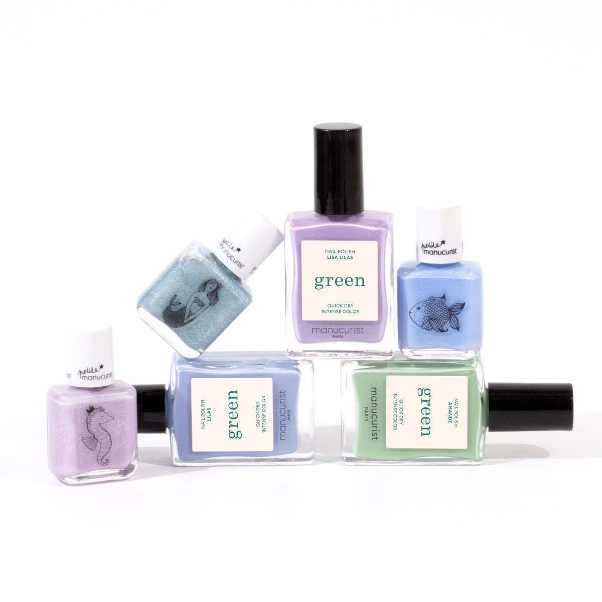 Six bottles of Manucurist’s You Me Under the Sea Green Set water-based nail polish in pastel aquatic shades (lavender, blue, mint green, purple) are arranged on white. Some green bottles feature sea animal illustrations on the labels.