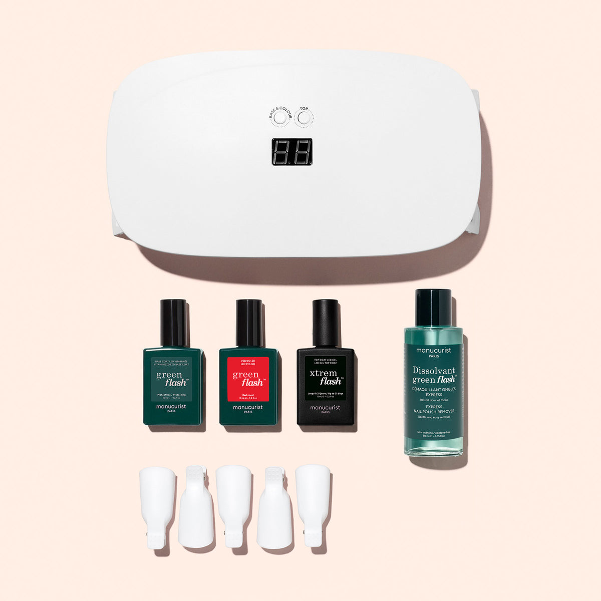 The Manucurist Discovery Kit—featuring a white UV lamp, three polishes, remover, and four clips—is displayed on a pale pink background, giving you all you need for an ultra-glossy gel manicure.