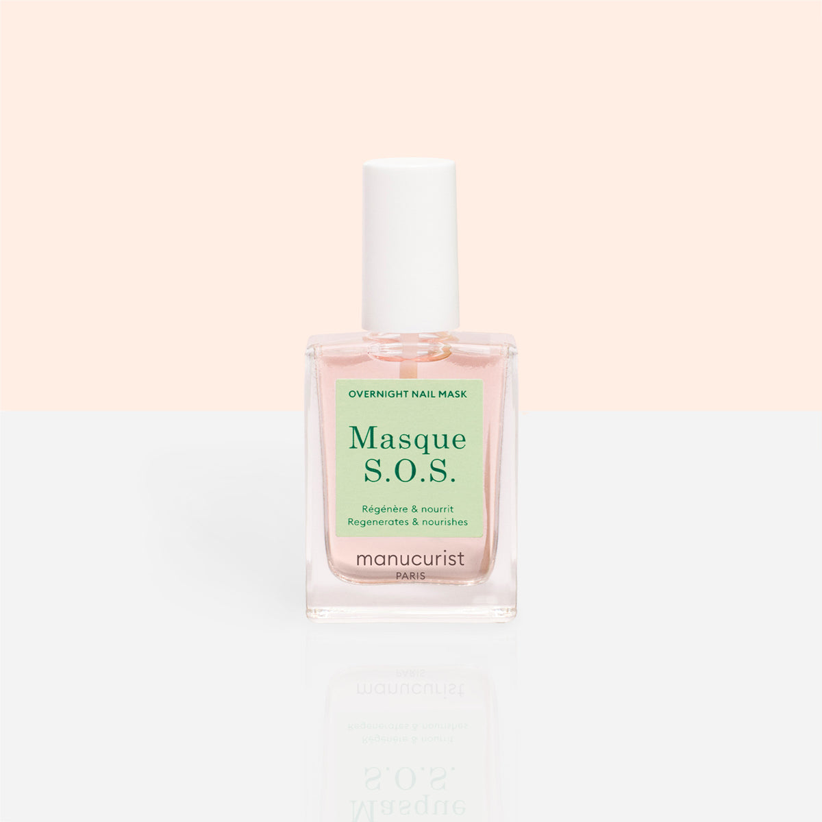 A clear glass bottle of Manucurist S.O.S. Nail Mask, a hydrating nail treatment with a white cap and light pink liquid, sits against a pastel peach and white background.