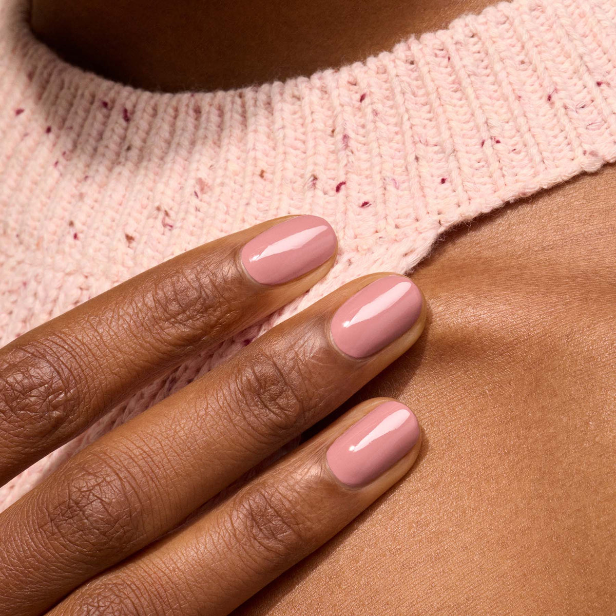 A close-up of a hand with short, neatly manicured nails painted in Manucurist’s Old Rose from the Green™ range, resting on a person&