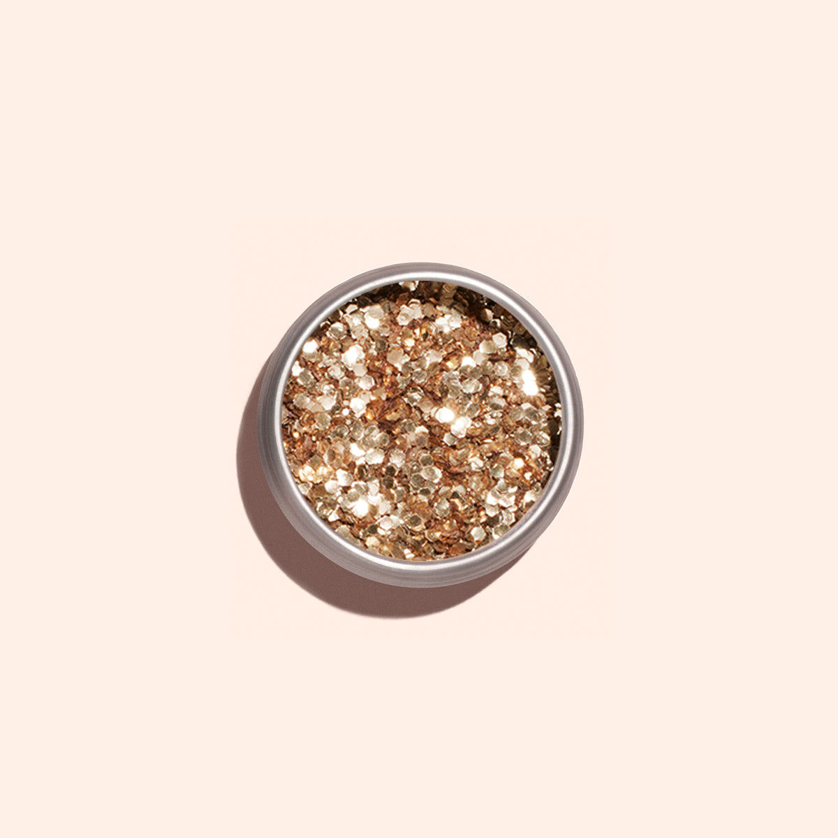 Un pot rond de paillettes biodégradables Rose Gold de Manucurist, parfaites pour le Nail Art, est posé sur un fond beige clair et projette une ombre douce.