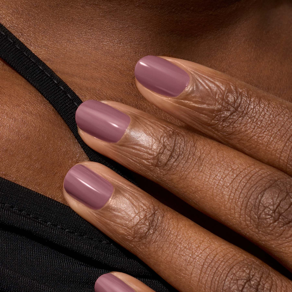 A close-up of a hand with medium brown skin, featuring neatly manicured nails painted in Manucurist&