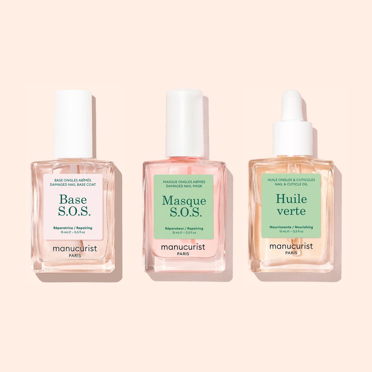 Trois flacons carrés du set Basic Routine - Damaged Nails de Manucurist sont présentés sur des fonds pastel avec des bouchons blancs, dont l’un est surmonté d’une pipette. Les étiquettes indiquent : Base S.O.S., Masque S.O.S. et Huile Verte, chacun formulé pour renforcer et réparer les ongles cassants.