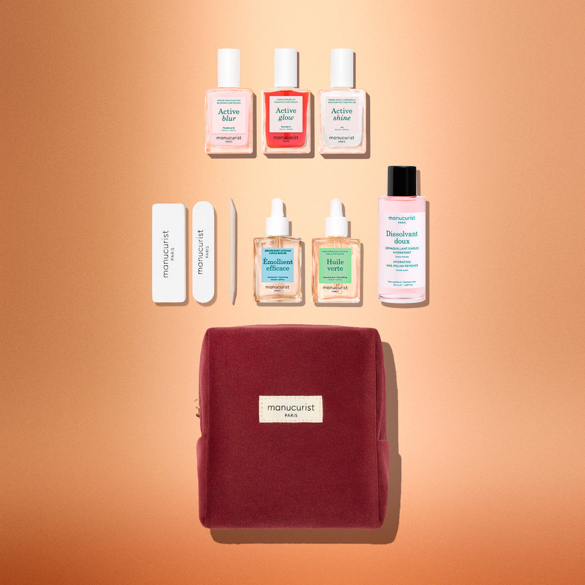 The Manucurist Active™ Starter Kit Gift Set features a chic burgundy manicure kit complete with nail polishes, remover, oils, files, and essential tools—all artfully arranged on a peach background. With the Manucurist label proudly displayed on the bag, this set is the perfect way to elevate your manicure routine and makes an ideal holiday gift for anyone who loves beautiful nails.