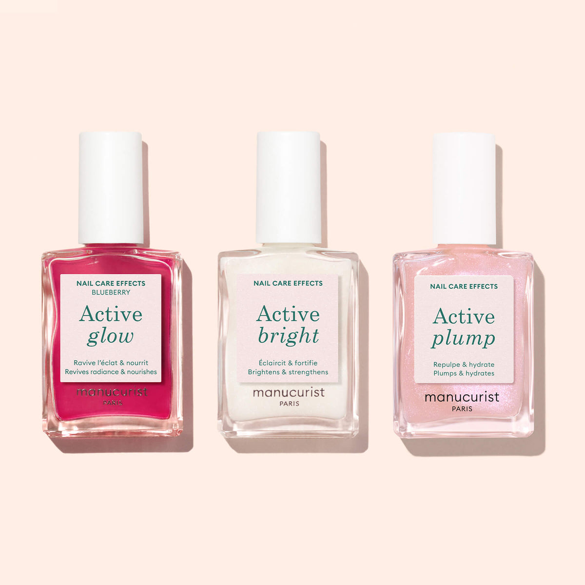 Three bottles of Manucurist nail care products are arranged side by side on a light pink background. Each bottle, crafted with plant-based formulas, features a different label: Active™ Glow Blueberry, Active Bright, and Active Plump—perfect nail enhancers for a healthier-looking manicure.