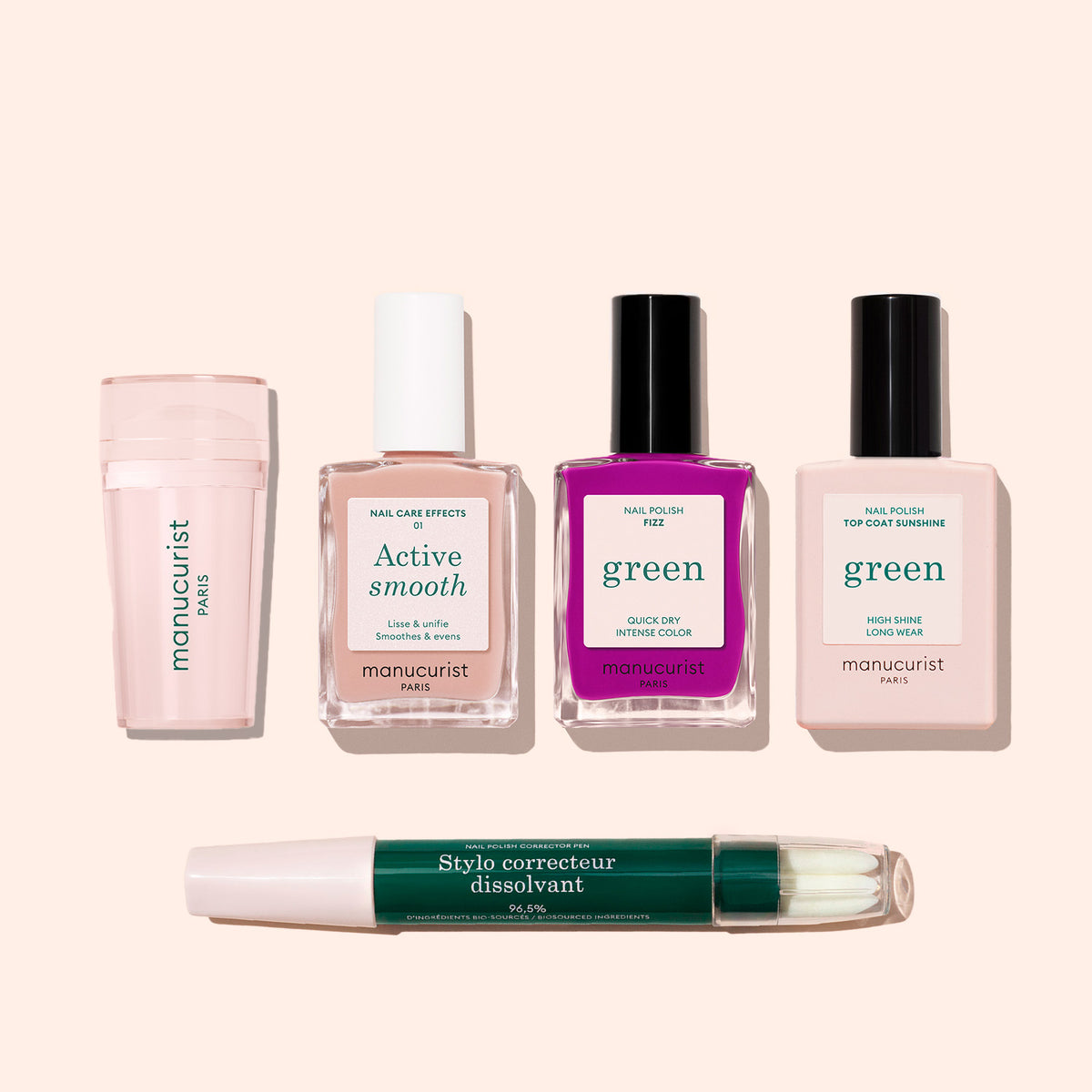 The Manucurist French Color Kit, featuring a cuticle remover, nail care bottle, bright and pale pink green-labeled polishes, and a dual-ended corrector pen, is displayed on a light beige background.