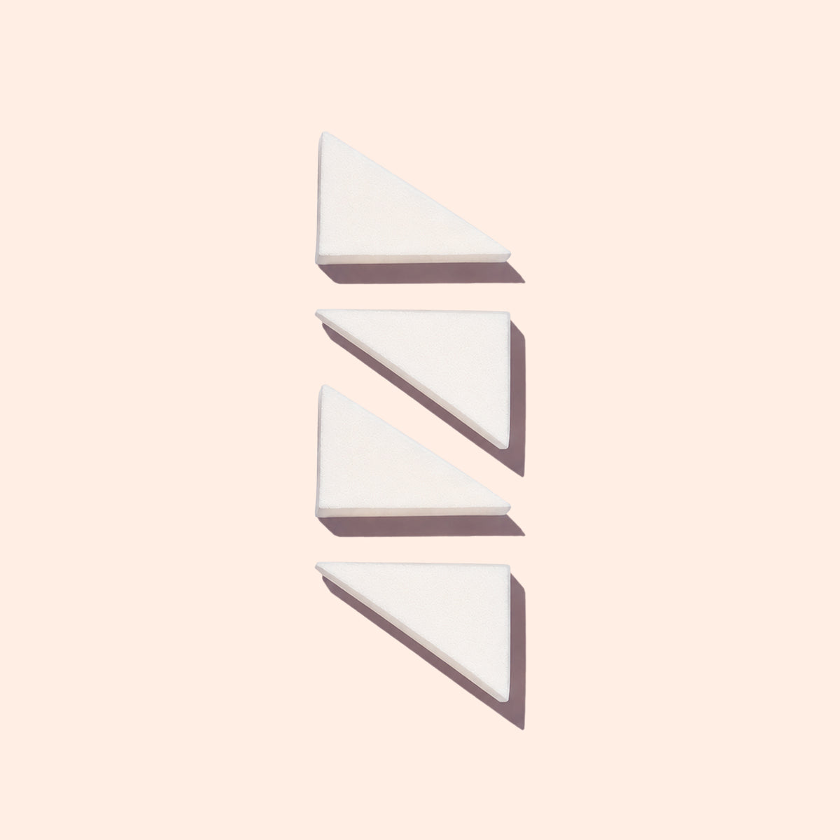 Quatre éponges triangulaires blanches Manucurist Nail Art sont disposées verticalement sur un fond pâle, chacune projetant une ombre douce vers la droite.