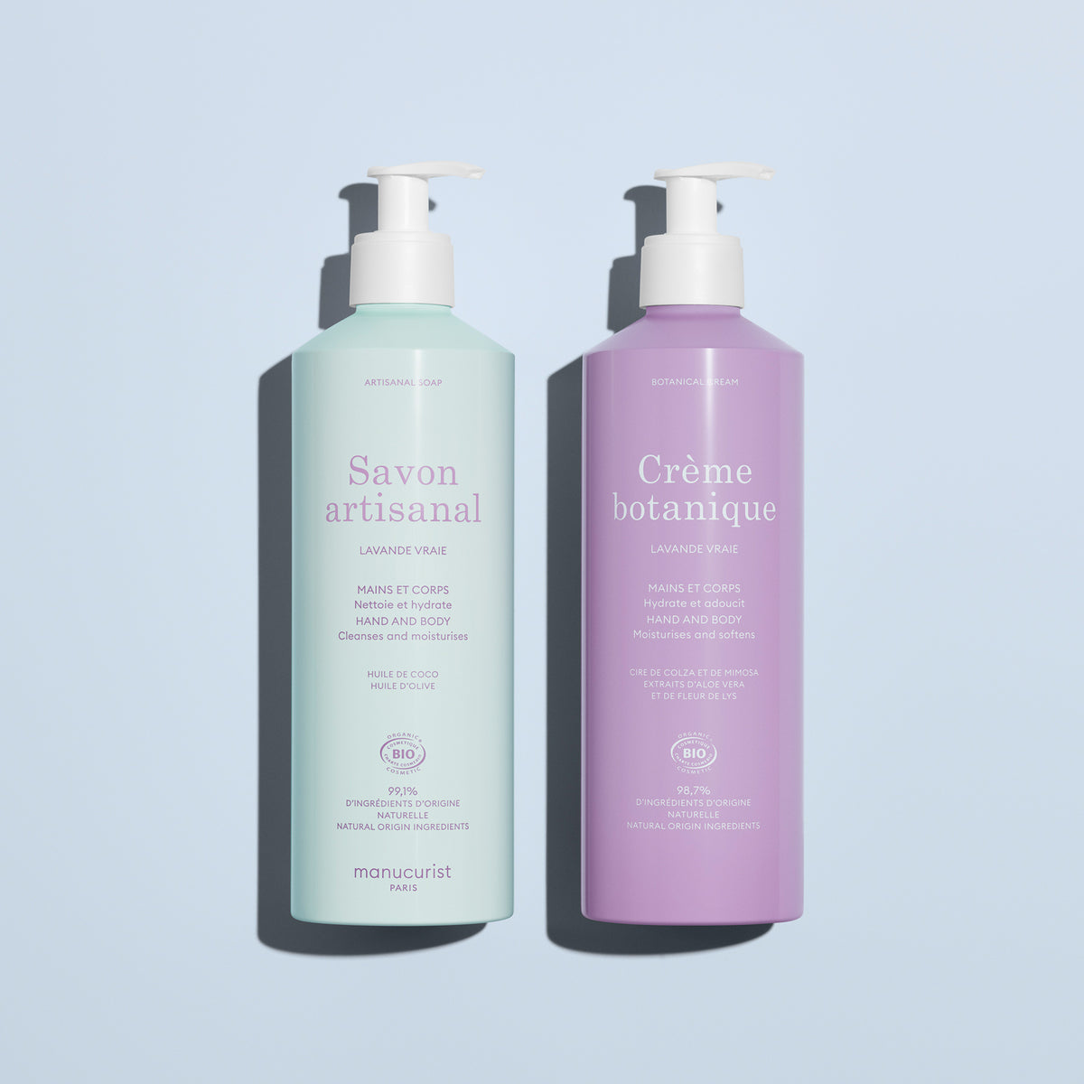 On a light blue background: two pump bottles by Manucurist, including the pale green "Artisan Soap" and the lavender "Organic Lavender Hand Body Wash - Cosmos Organic," both for hands and body.