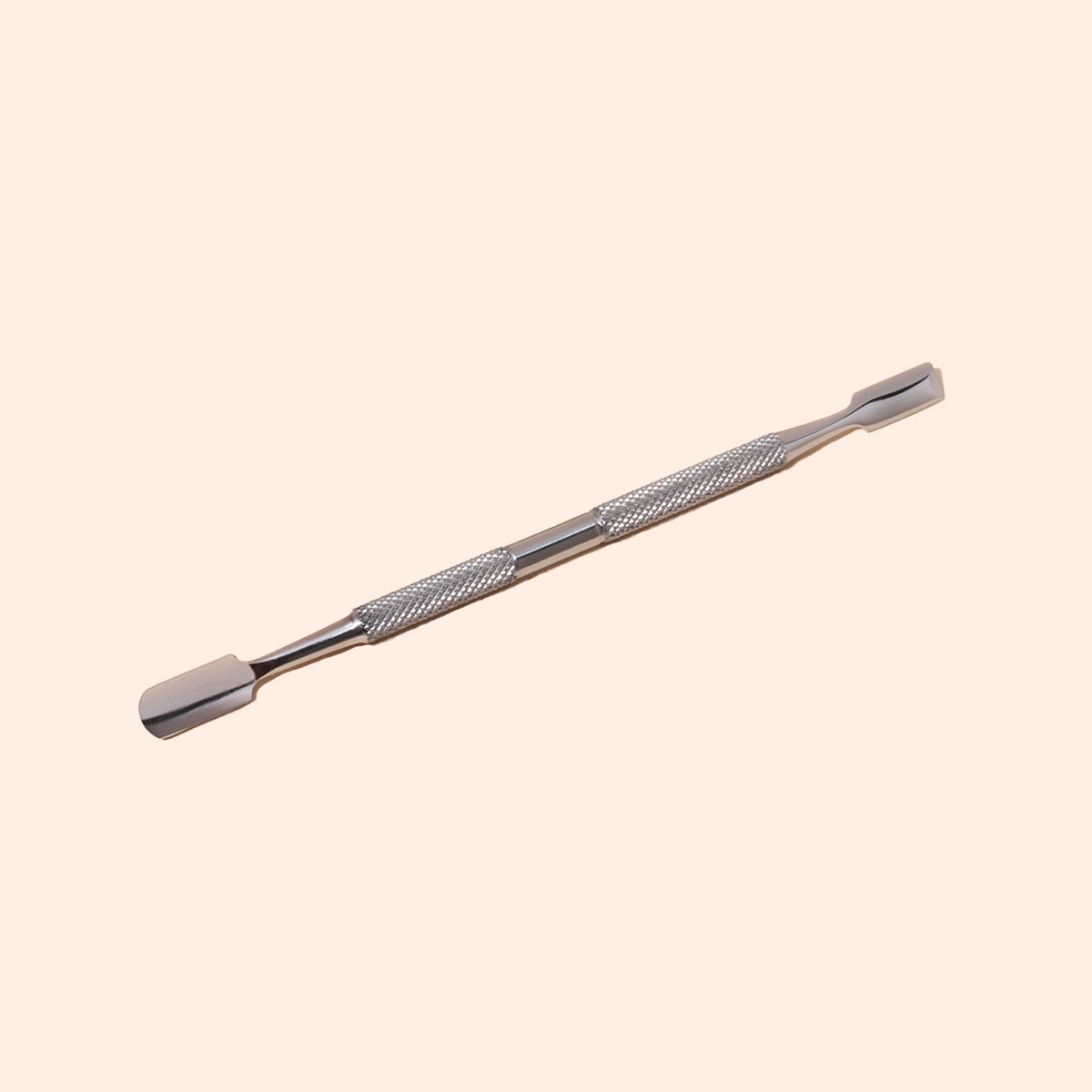 The Manucurist Cuticle Pusher, made of stainless steel with a textured grip and dual flat, rounded tips, is shown on a light beige background—an essential tool for precise nail care.