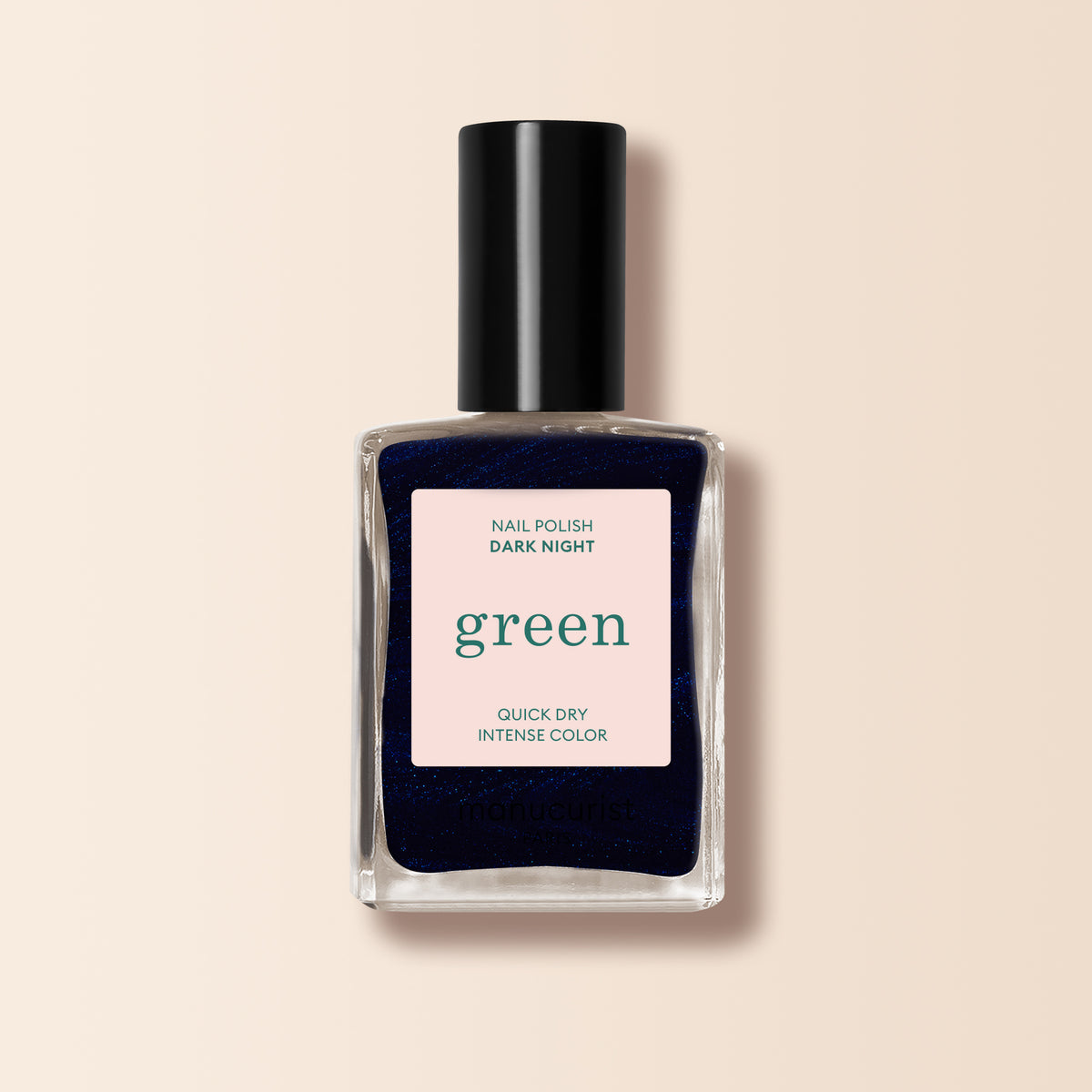Un flacon carré en verre de vernis à ongles Manucurist Dark Night, teinte bleu nuit avec un bouchon noir. L’étiquette indique Dark Night, gamme Green™, Quick Dry Intense Color, sur fond pâle.