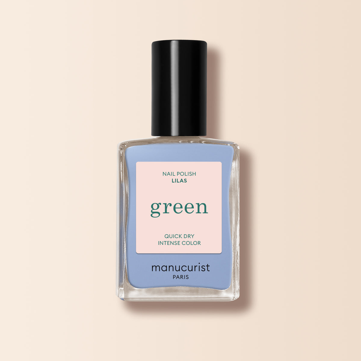 Un flacon de vernis à ongles Manucurist Lilas avec un bouchon noir et l’étiquette « Nail Polish Lilas, Quick Dry, Intense Color » est posé sur un fond beige clair à côté d’un vernis bleu pastel.