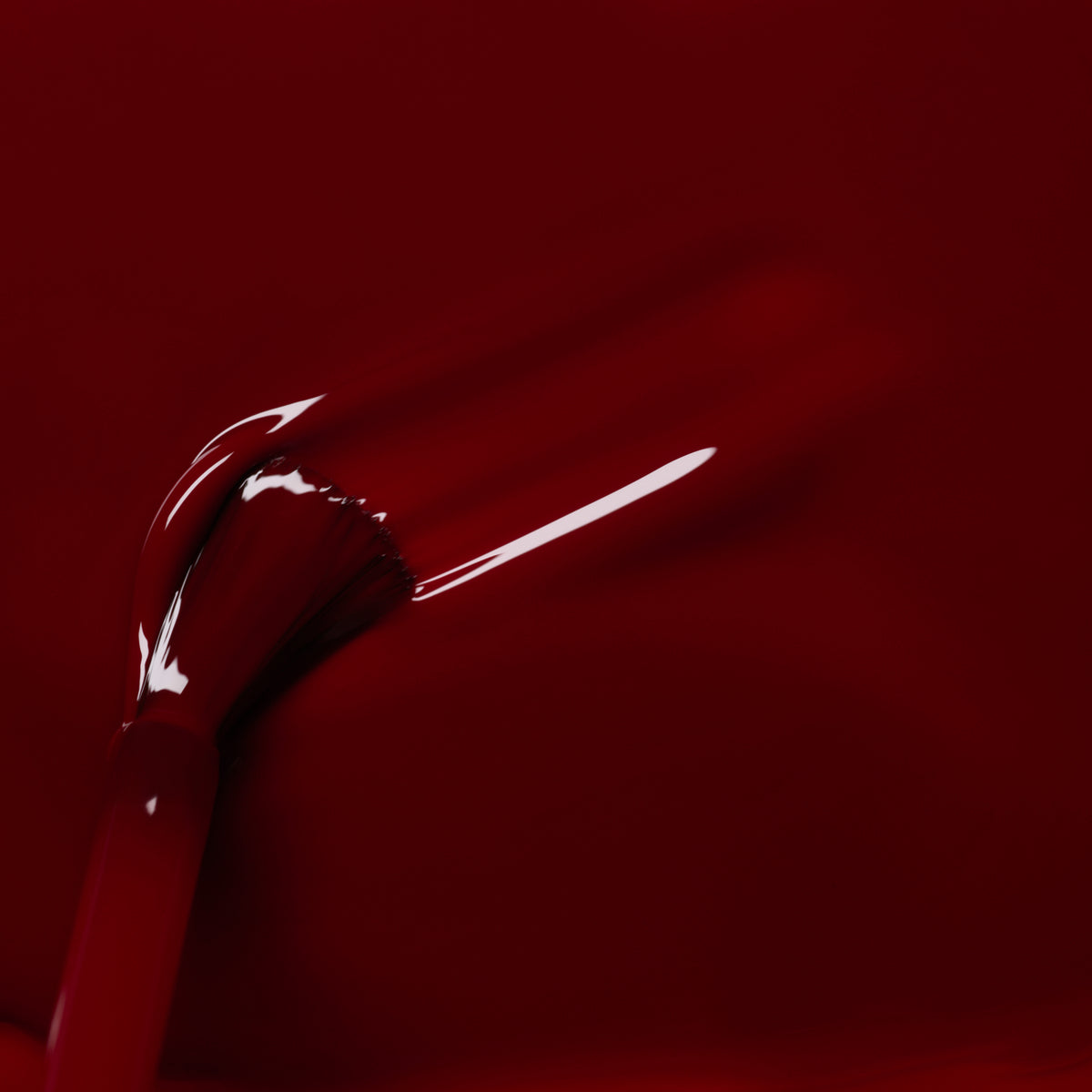 A close-up of a Manucurist brush applying glossy Dark Pansy from the Green™ range on a smooth surface, showcasing visible brush strokes and a reflective shine.