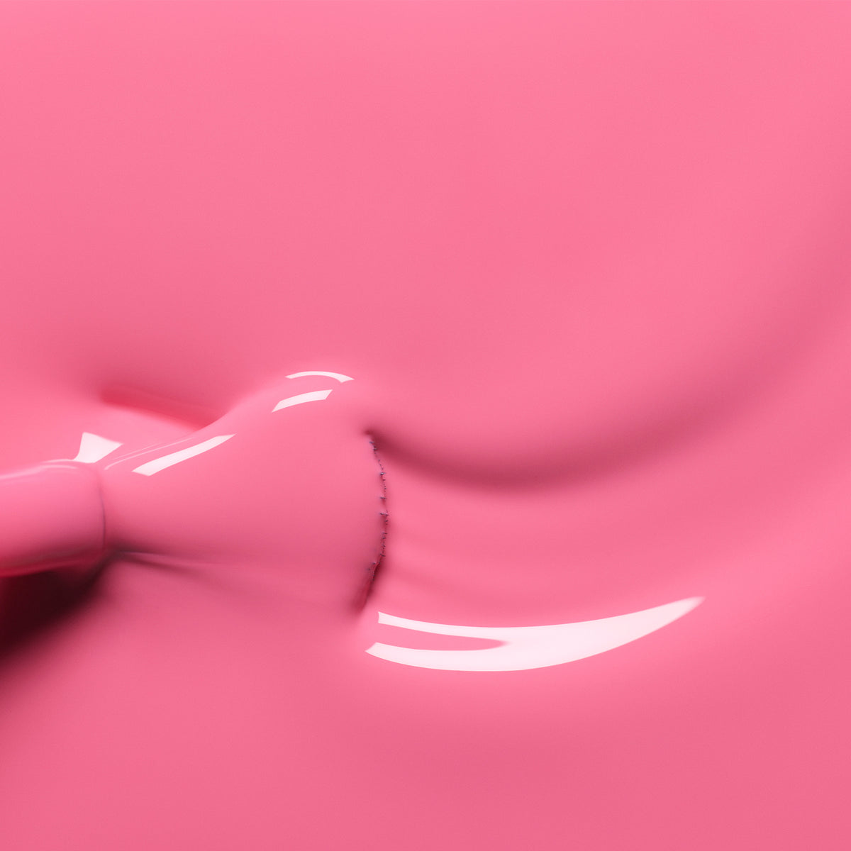 Gros plan sur le vernis à ongles Rose de Manucurist qui s’étale uniformément, révélant des reflets brillants à la surface du liquide, tandis qu’un pinceau est partiellement visible à gauche.