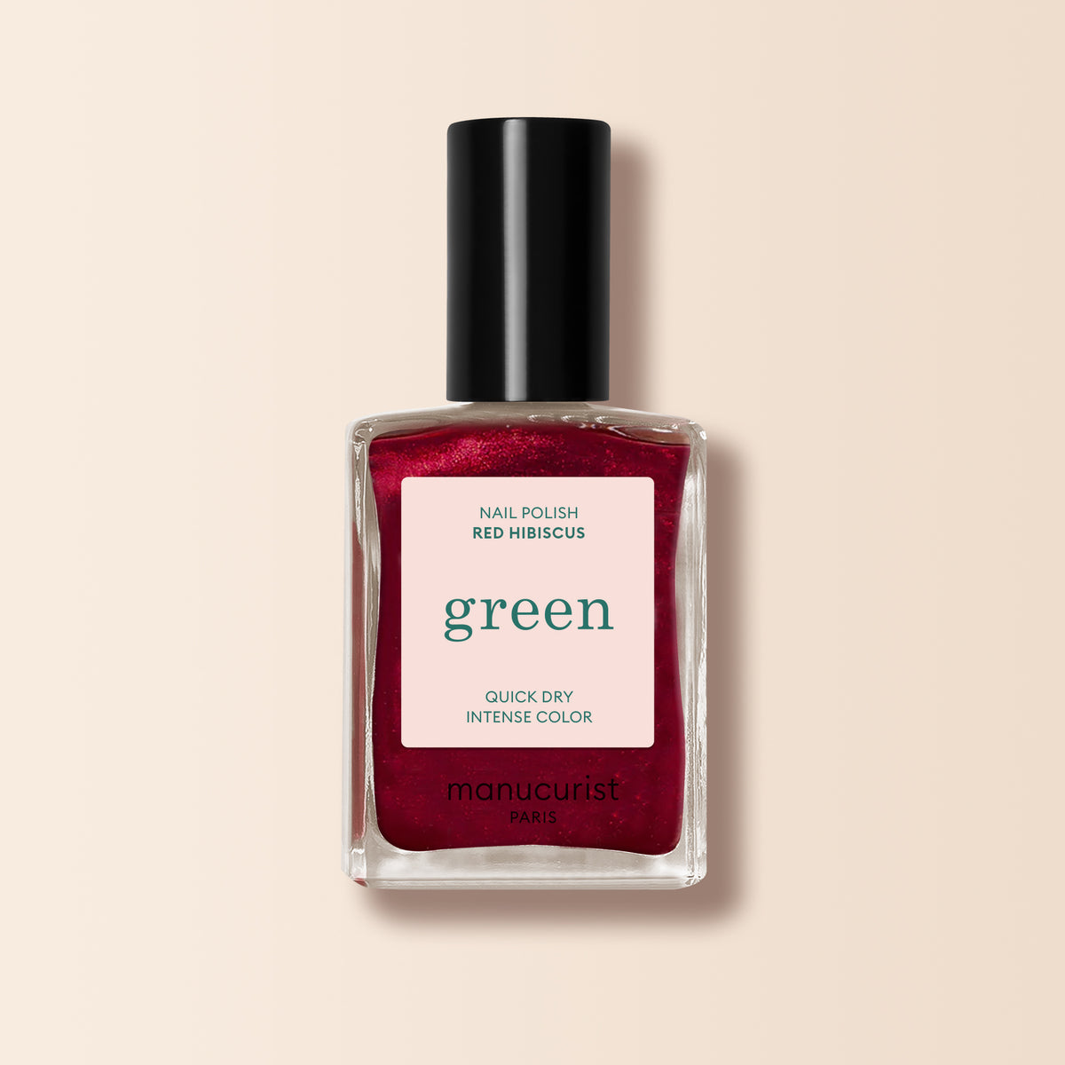 Un flacon en verre transparent de vernis à ongles Manucurist Red Hibiscus avec un bouchon noir et une étiquette indiquant « Quick Dry Intense Color » est présenté, avec le nom du produit sur un fond clair.