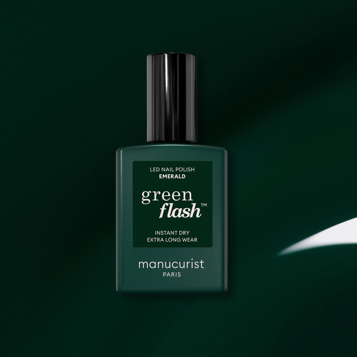 Un flacon de vernis semi-permanent LED Green Flash de Manucurist en teinte Emerald est placé au centre d’un fond vert foncé. Les mentions « Instant Dry » et « Extra Long Wear » figurent sur l’étiquette et soulignent l’allure riche et raffinée de ce vernis inspiré d’une pierre précieuse.