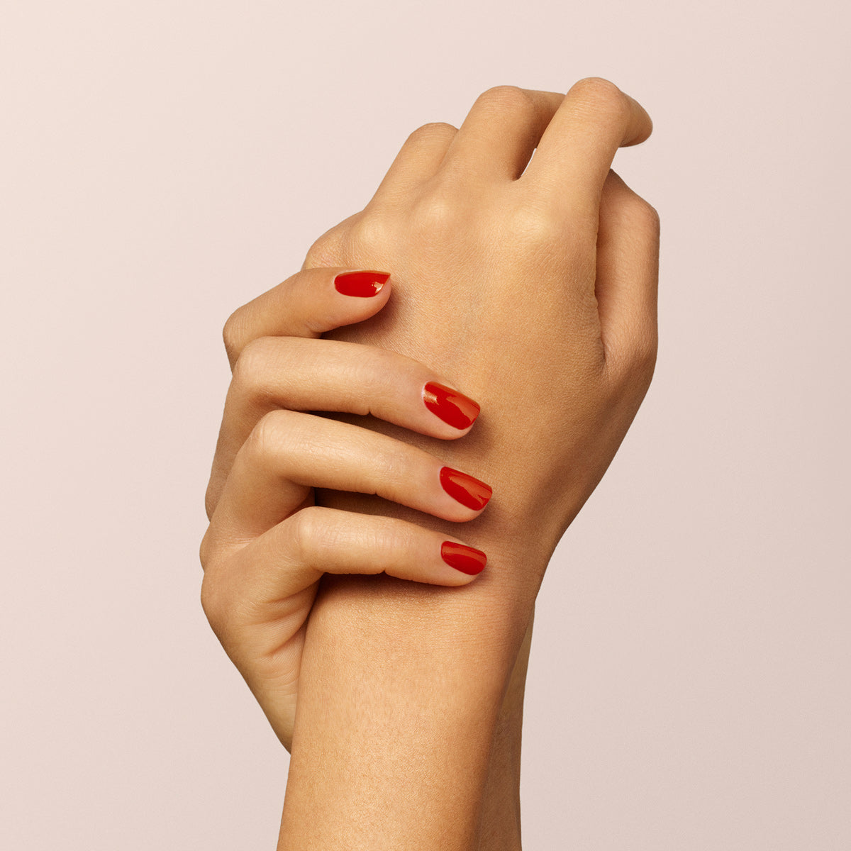 Two hands are shown against a plain, light background. One gently holds the wrist of the other, showcasing neatly manicured nails painted with Manucurist&