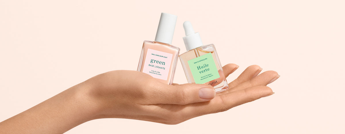 A hand holds two glass bottles of facial serums with dropper tops and green labels against a light beige background. One label reads green and the other reads Huile verte.