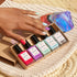 A hand with multicolored nails rests on a woven mat beside an iridescent stone, holding Manucurist&