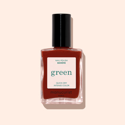 Un flacon de vernis Manucurist Bohème, portant les mentions "green" et "COULEUR INTENSE SÉCHAGE RAPIDE," présente un rouge profond aux sous-tons bruns et un bouchon noir, sur fond beige clair.