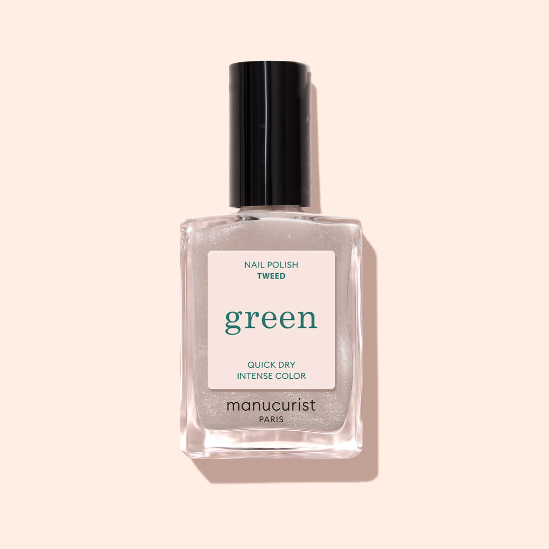 A bottle of Manucurist Tweed nail polish, a soft grey shade with pearly undertones and a black cap, is set against a light pink background.