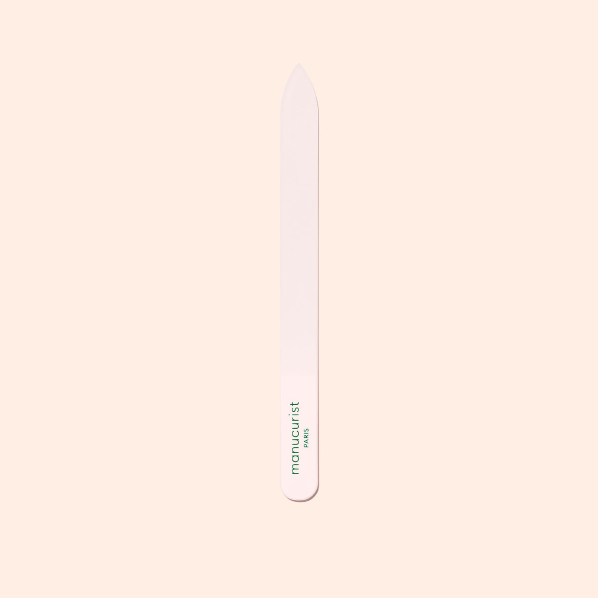 The Manucurist-us Glass Nail File features a pointed tip and "manucurist" in green near the base, shown vertically on a pale beige background.