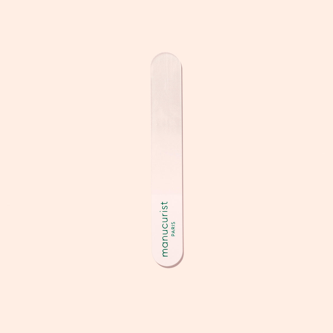 A Manucurist-us Glass Polisher with rounded ends rests on a pale surface. “Manucurist-us” is printed vertically in green, making it ideal for gently enhancing the natural shine of your nail plate.