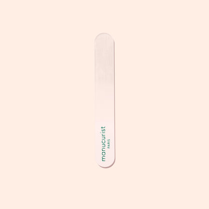 A Manucurist-us Glass Polisher with rounded ends rests on a pale surface. “Manucurist-us” is printed vertically in green, making it ideal for gently enhancing the natural shine of your nail plate.