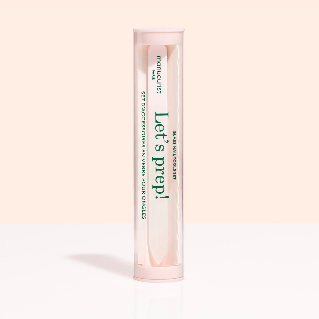 A cylindrical, clear container with a pink lid and base holds the Glass nail accessory trio by Manucurist-us. The label says "Lets prep!" and "manucurist Paris," with text in English and French.