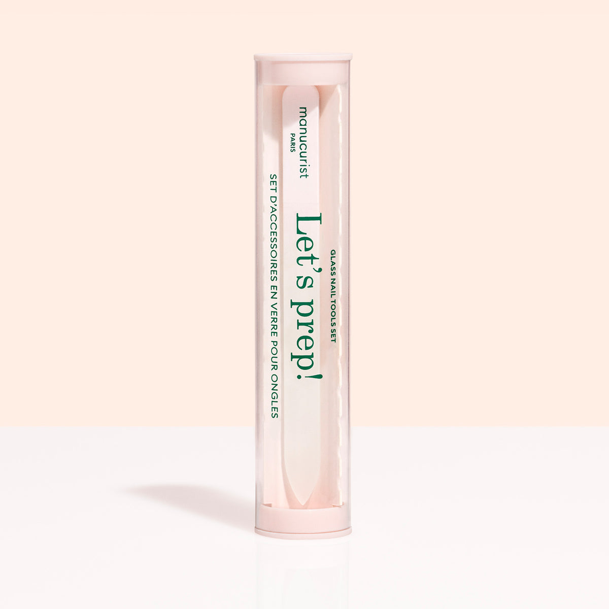 Un contenant cylindrique transparent avec un couvercle et une base roses contient le trio d’accessoires pour ongles Glass de Manucurist-us. L’étiquette indique "Lets prep!" et "manucurist Paris,", avec du texte en anglais et en français.