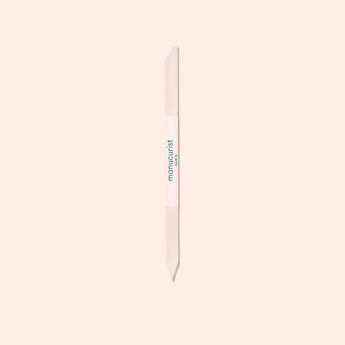 The Manucurist Glass Cuticle Pusher features a pointed tip and beveled edge for precise nail contouring, with "manucurist" in green on a white center section, displayed on a light beige background.