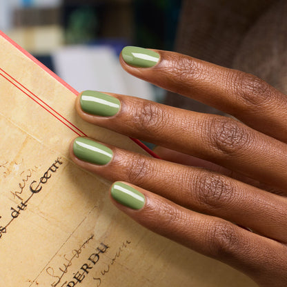 A close-up of a hand with medium brown skin and neatly manicured nails painted in Manucurist&