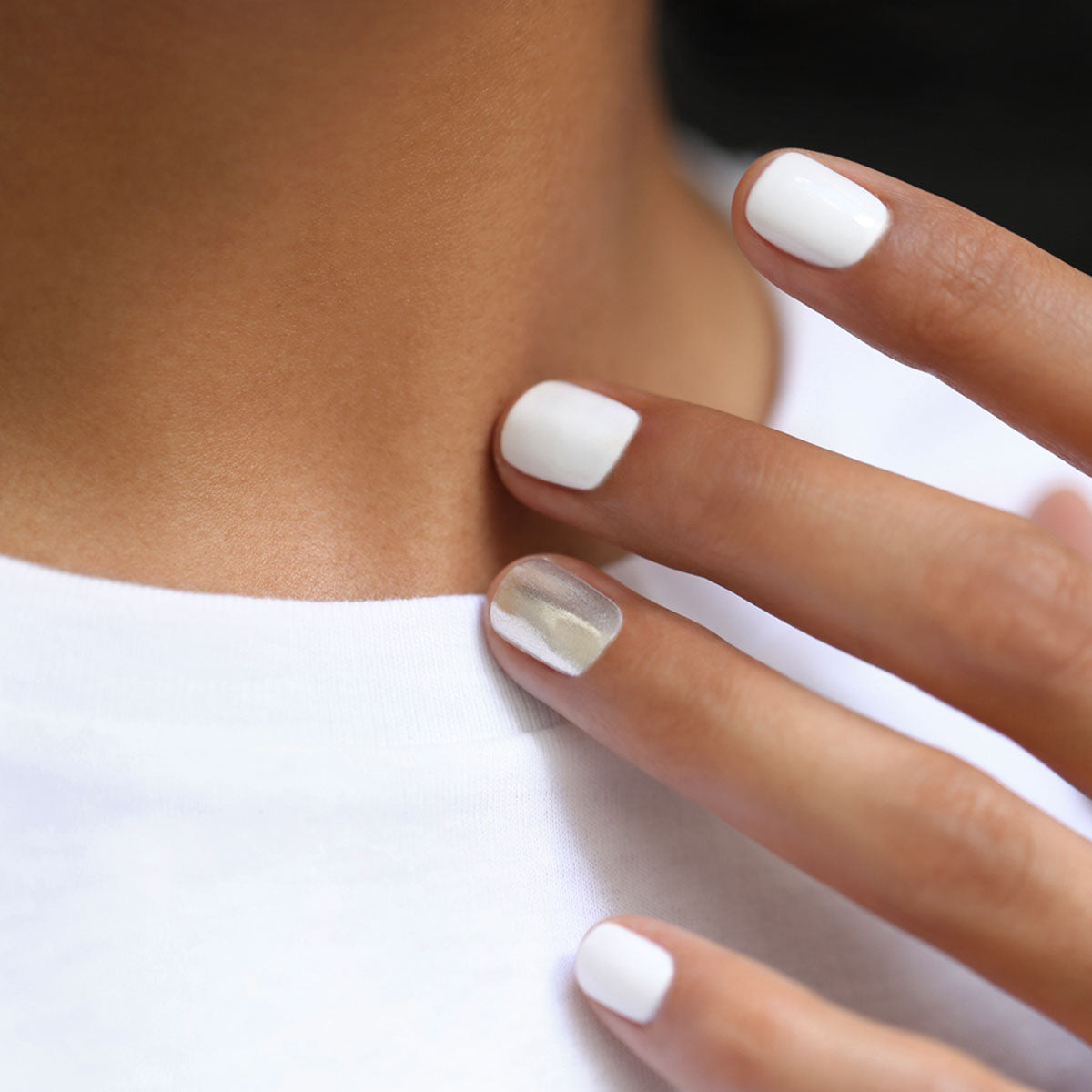 Un gros plan montre une personne portant une chemise blanche aux ongles soigneusement manucurés — quatre blancs, l’annulaire argent métallisé — avec un fard à paupières rouge, blanc et bleu audacieux. Elle présente le Trio Red, White Blue de Manucurist pour un look patriotique remarquable.