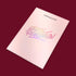 A pale pink booklet on a dark red background highlights the Manucurist US Gift Card, with holographic "GREEN REVOLUTION" text—an inspiring choice for green gifting.