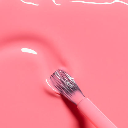 A close-up of a brush with pink bristles resting on the smooth, glossy surface of Manucurist&