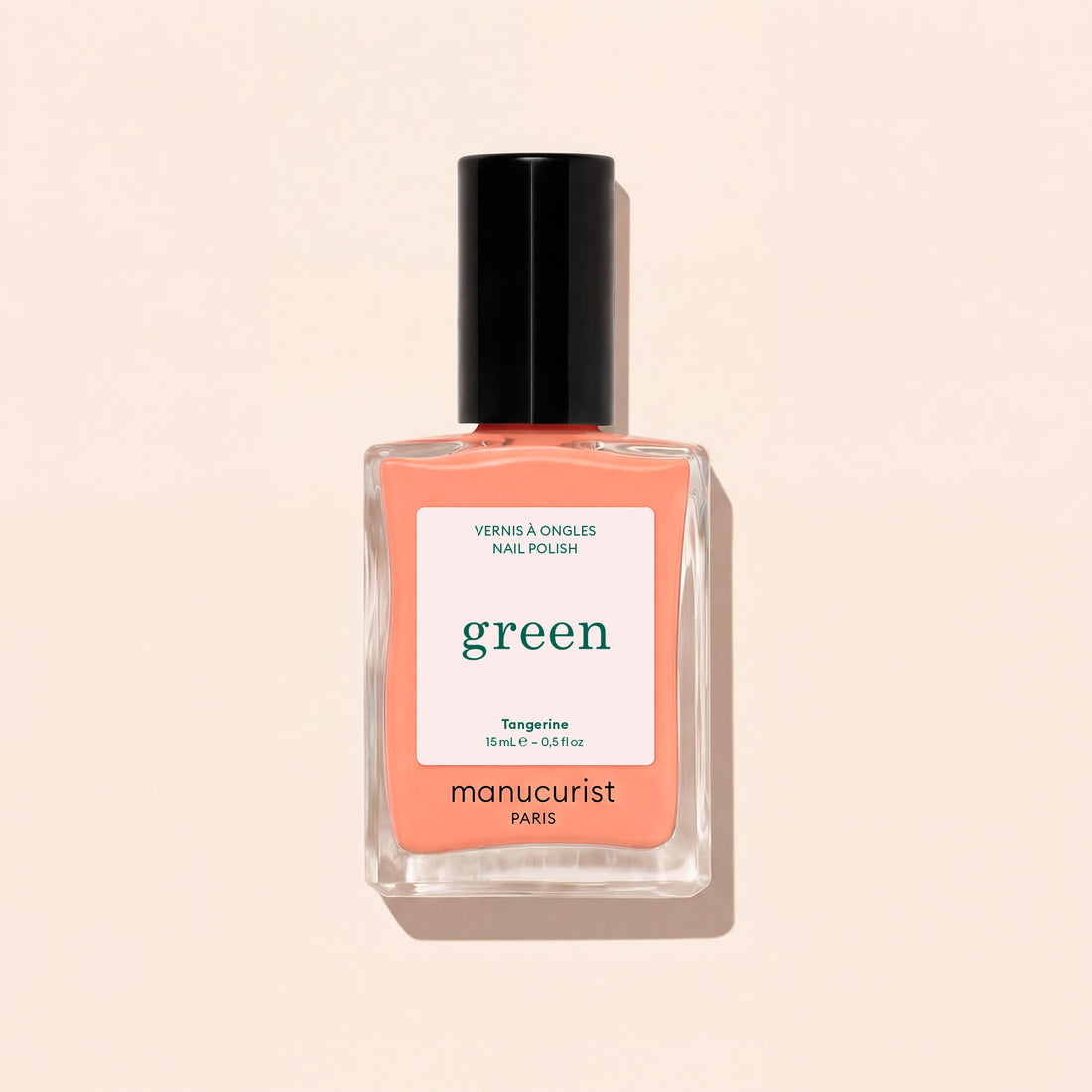Le vernis à ongles Tangerine de Manucurist présente une teinte orange clair, avec un bouchon noir et une étiquette blanche ornée de texte vert et noir, sur un fond beige clair. Cette couleur vibrante apporte une touche vive à votre look.