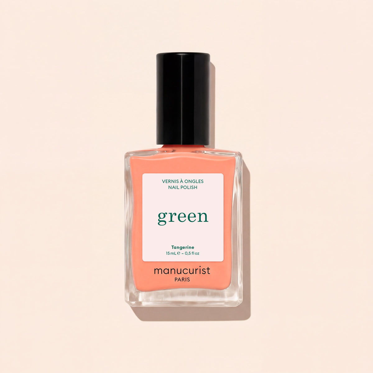 Le vernis à ongles Tangerine de Manucurist présente une teinte orange clair, avec un bouchon noir et une étiquette blanche ornée de texte vert et noir, sur un fond beige clair. Cette couleur vibrante apporte une touche vive à votre look.