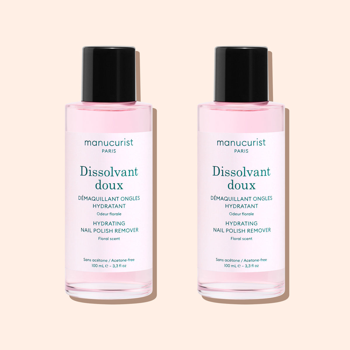 Two bottles of Manucurist Gentle Remover, featuring pale pink, acetone-free liquid with black caps and white labels, are placed side by side on a light beige background.