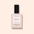 A bottle of Manucurist Glitter Top Coat, in a pale pink square bottle with a black cap and white label on a light beige background, offers an express air-drying formula for a smooth, gel-like finish.